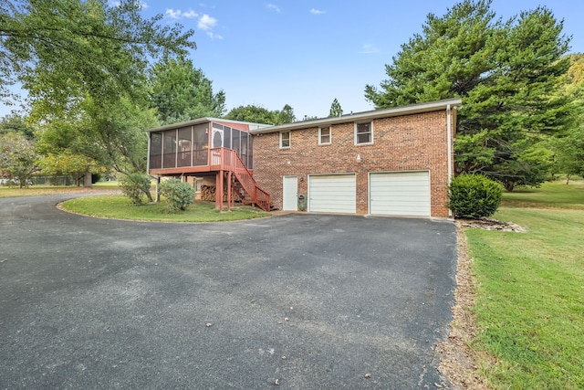 view of front of home with a front yard, a garage, and a sunroom