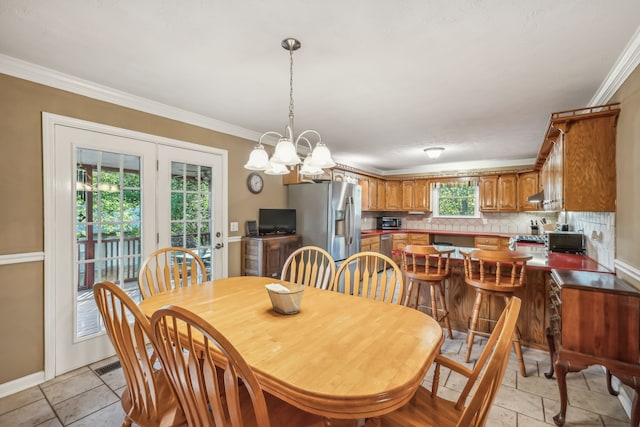 dining space featuring a notable chandelier, a wealth of natural light, and ornamental molding