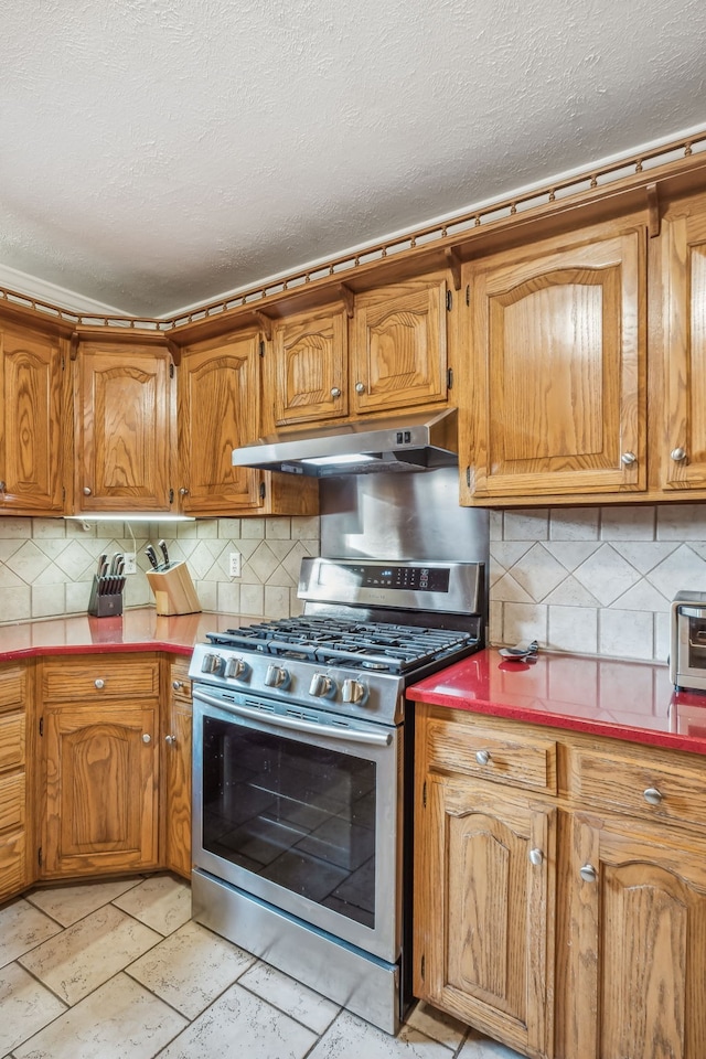 kitchen with a textured ceiling, stainless steel gas stove, and tasteful backsplash