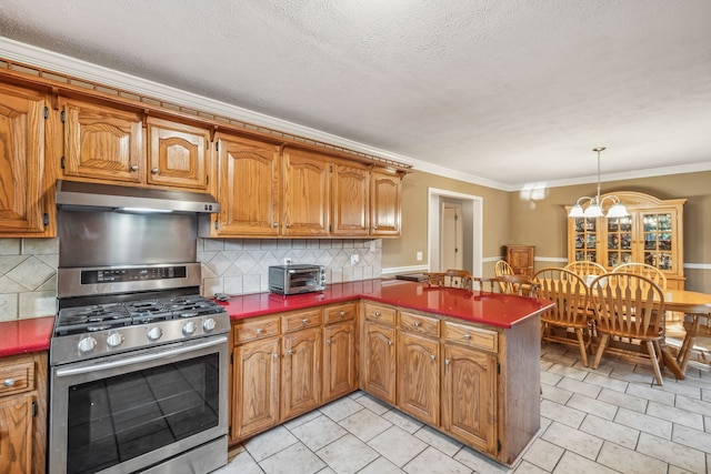 kitchen with decorative backsplash, gas range, pendant lighting, and ornamental molding