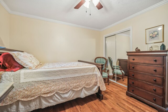 bedroom featuring ornamental molding, a closet, light hardwood / wood-style floors, and ceiling fan