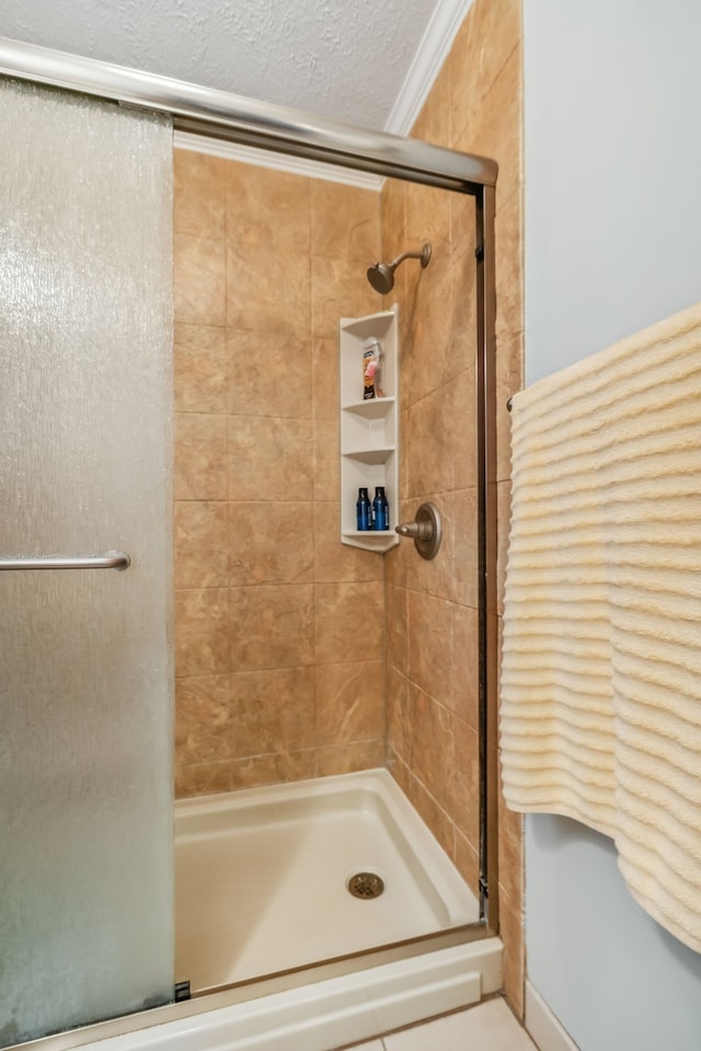 bathroom featuring a textured ceiling, ornamental molding, and an enclosed shower