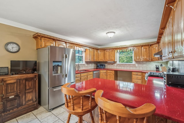 kitchen with appliances with stainless steel finishes, backsplash, sink, and crown molding