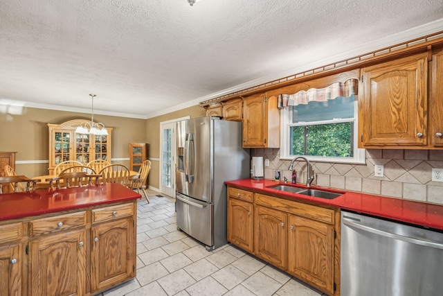 kitchen with pendant lighting, sink, stainless steel appliances, backsplash, and ornamental molding