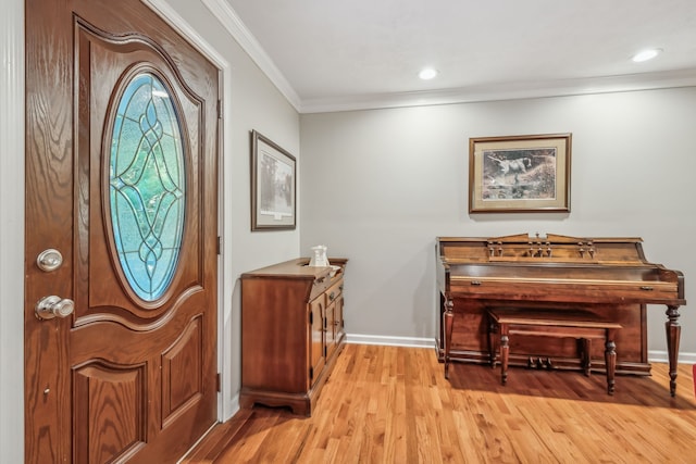 entrance foyer with ornamental molding and light hardwood / wood-style flooring