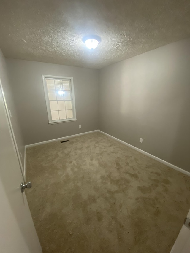 spare room featuring a textured ceiling and carpet