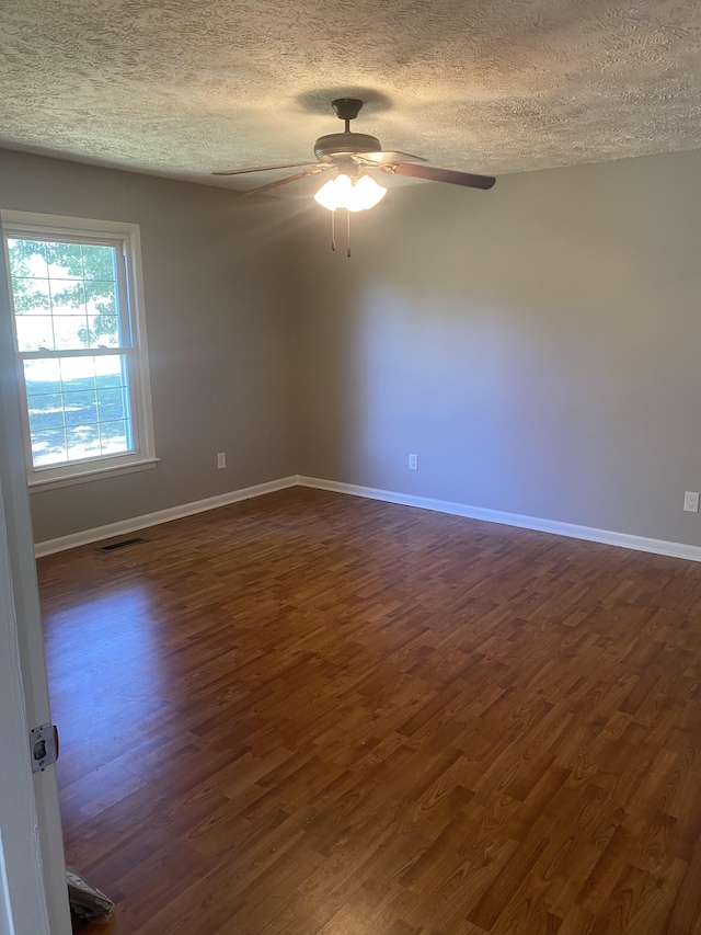 empty room featuring ceiling fan, a textured ceiling, and dark hardwood / wood-style flooring