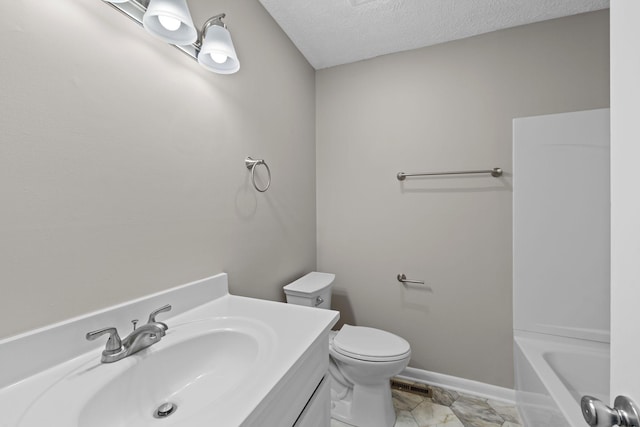 bathroom featuring a tub to relax in, vanity, toilet, and a textured ceiling