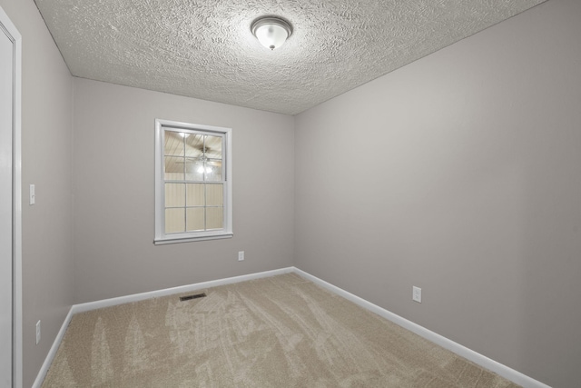 carpeted empty room featuring a textured ceiling