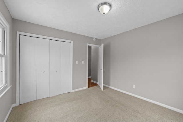 unfurnished bedroom with carpet floors, a textured ceiling, and a closet