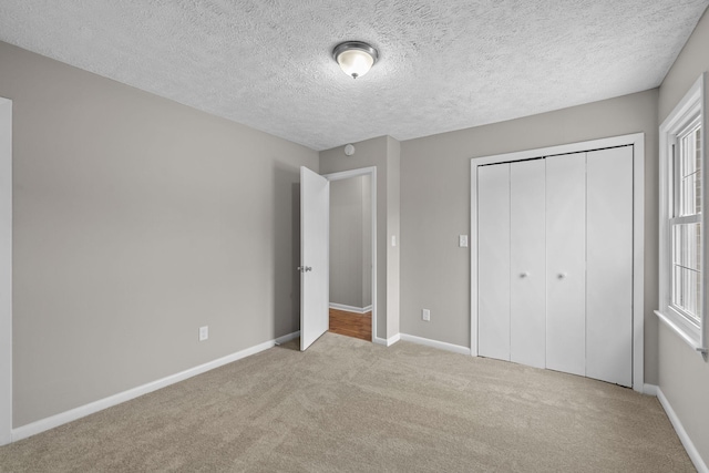 unfurnished bedroom featuring light colored carpet, a closet, and a textured ceiling