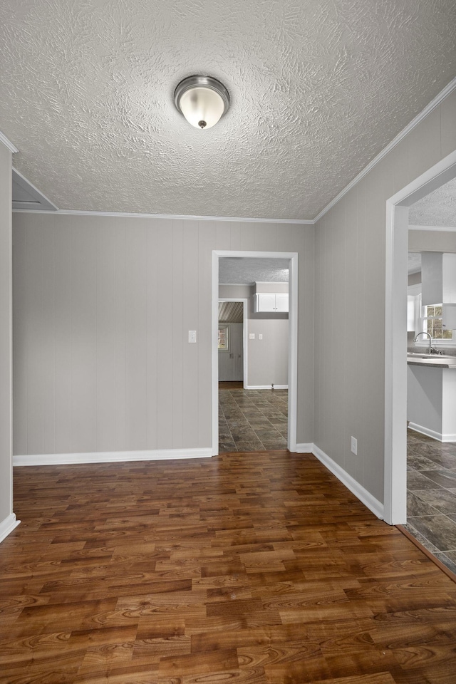 spare room with ornamental molding, dark hardwood / wood-style floors, sink, and a textured ceiling