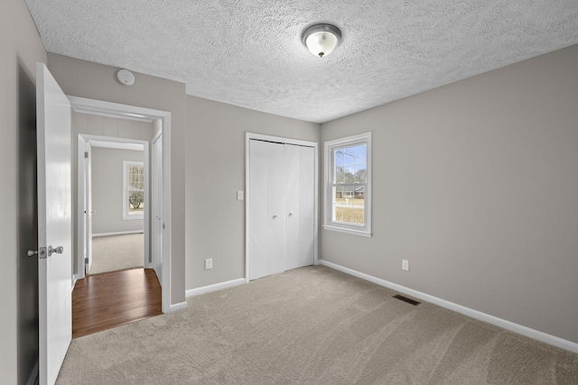 unfurnished bedroom with a closet, light carpet, and a textured ceiling