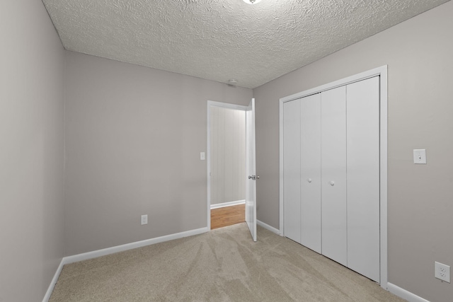 unfurnished bedroom with a closet, light carpet, and a textured ceiling