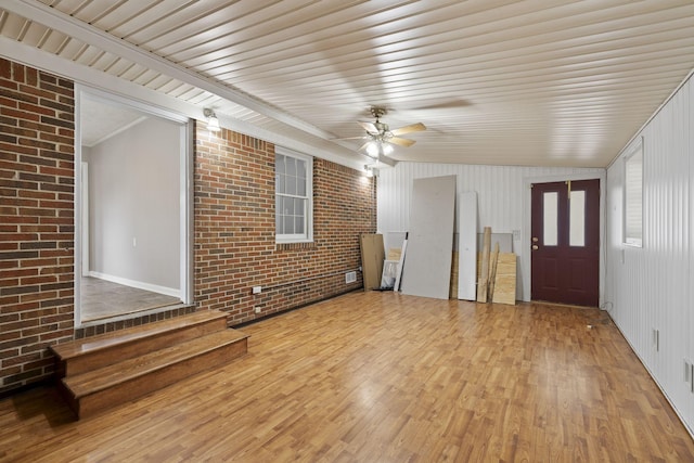 interior space featuring ceiling fan, brick wall, and light hardwood / wood-style floors