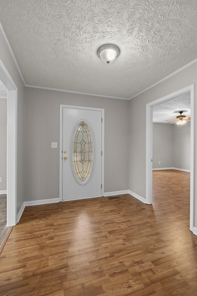 entrance foyer with ceiling fan, ornamental molding, hardwood / wood-style floors, and a textured ceiling