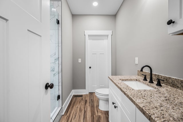 bathroom featuring hardwood / wood-style flooring, vanity, toilet, and a shower with door