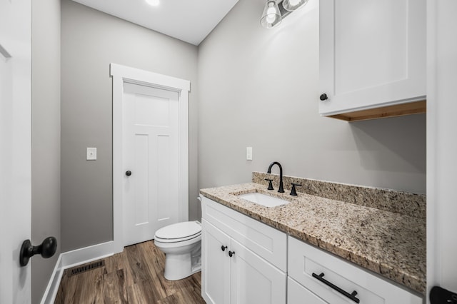 bathroom with hardwood / wood-style flooring, vanity, and toilet