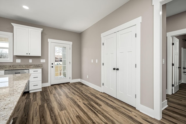 kitchen with stainless steel dishwasher, dark hardwood / wood-style floors, light stone countertops, and white cabinets