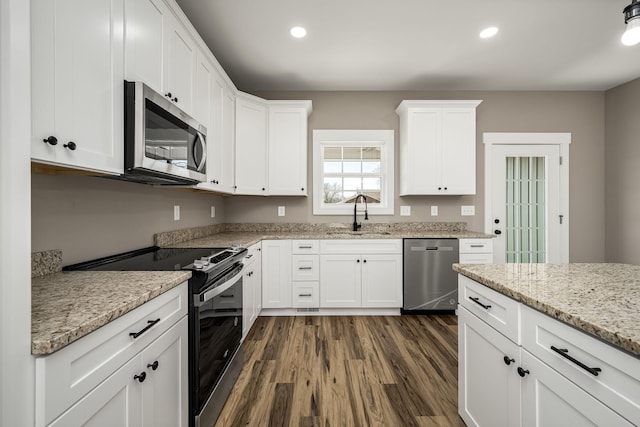 kitchen with dark wood-type flooring, sink, white cabinetry, light stone counters, and stainless steel appliances