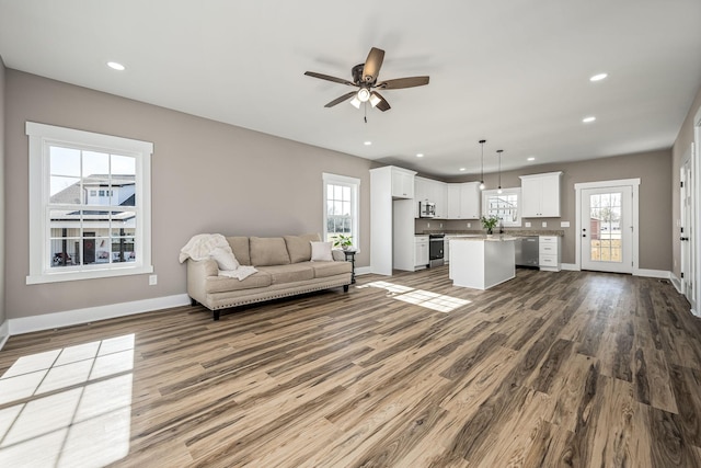 unfurnished living room featuring a healthy amount of sunlight, hardwood / wood-style floors, and ceiling fan