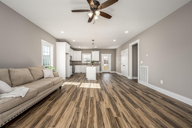 unfurnished living room featuring sink, dark wood-type flooring, and ceiling fan