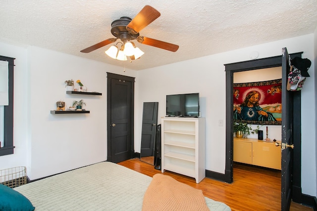 bedroom featuring ceiling fan, wood-type flooring, and a textured ceiling