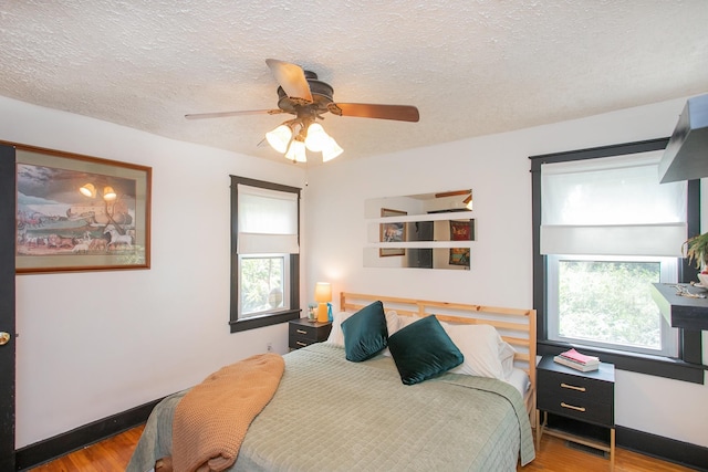 bedroom with ceiling fan, a textured ceiling, and hardwood / wood-style flooring