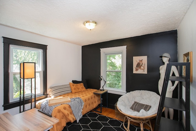 bedroom with wood-type flooring, a textured ceiling, and multiple windows