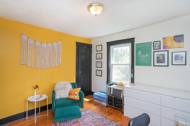 living area featuring a textured ceiling and hardwood / wood-style flooring