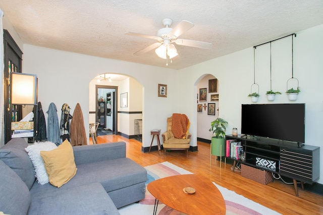 living room featuring wood-type flooring, a textured ceiling, and ceiling fan