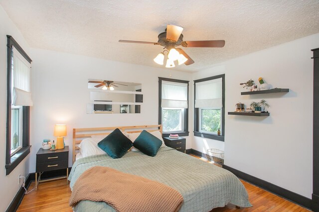 bedroom with ceiling fan, light wood-type flooring, and a textured ceiling