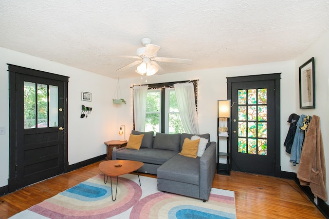 living room featuring ceiling fan, plenty of natural light, a textured ceiling, and light hardwood / wood-style flooring