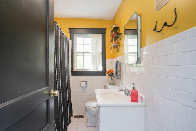 bathroom with tile patterned flooring, vanity, toilet, and tile walls