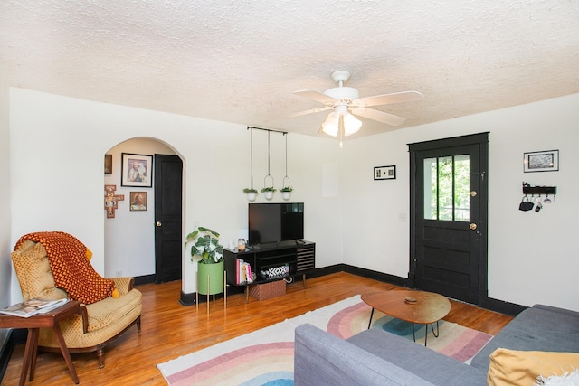 living room with ceiling fan, wood-type flooring, and a textured ceiling