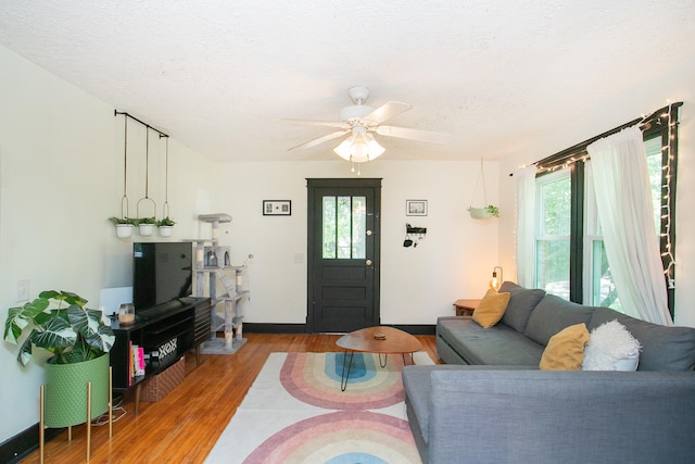 living room featuring wood-type flooring, a textured ceiling, ceiling fan, and a healthy amount of sunlight