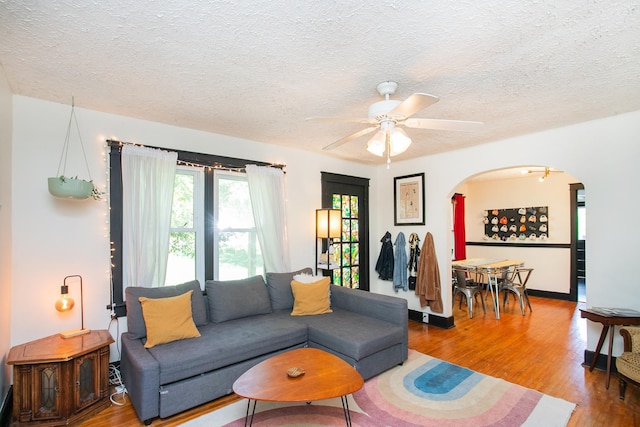 living room with ceiling fan, wood-type flooring, and a textured ceiling