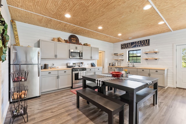 dining room featuring light wood-type flooring, wood walls, wooden ceiling, and a wealth of natural light