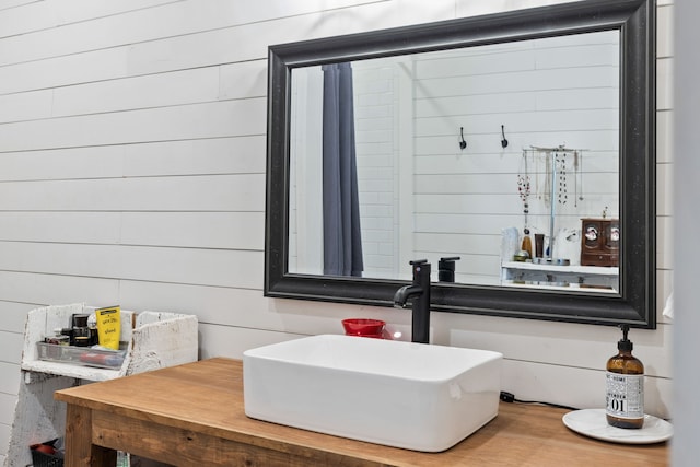 bathroom featuring wooden walls and sink