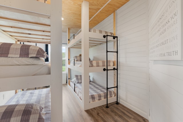 bedroom with wooden walls, wooden ceiling, and hardwood / wood-style floors