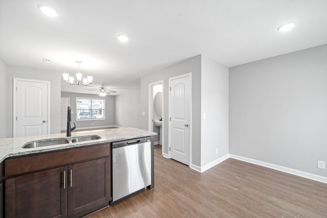 kitchen featuring pendant lighting, dishwasher, light stone counters, sink, and light hardwood / wood-style flooring