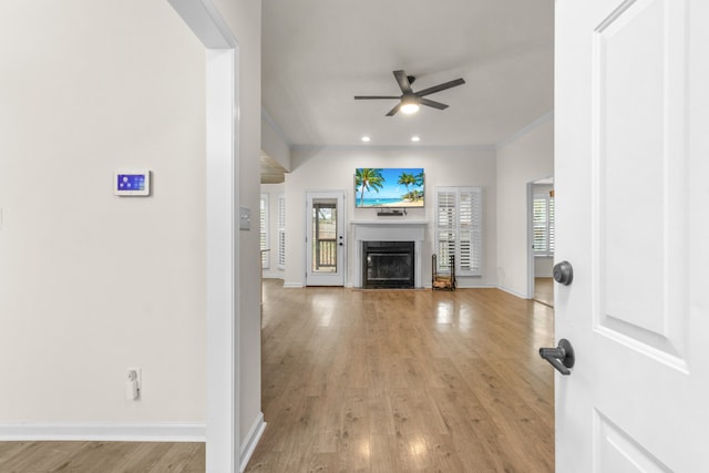 unfurnished living room with light wood-type flooring, ceiling fan, and crown molding