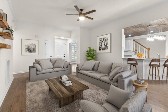 living room with hardwood / wood-style flooring, ceiling fan, and ornamental molding