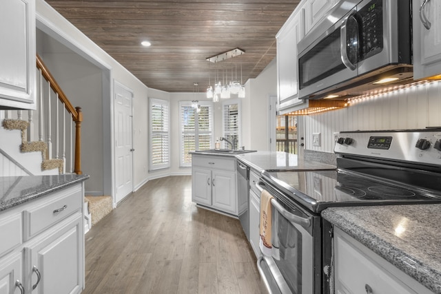 kitchen featuring white cabinets, pendant lighting, light wood-type flooring, and stainless steel appliances