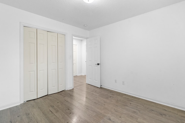 unfurnished bedroom with a closet, a textured ceiling, and light wood-type flooring