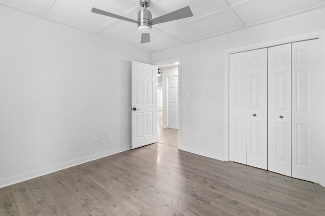 unfurnished bedroom featuring ceiling fan, wood-type flooring, and a closet