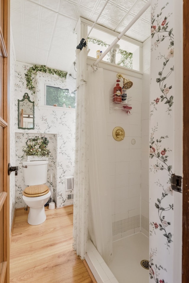 bathroom with hardwood / wood-style floors, toilet, and a shower with shower curtain