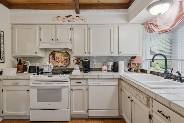 kitchen with light hardwood / wood-style floors, tasteful backsplash, white appliances, tile counters, and sink