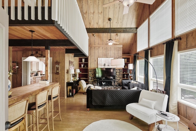 living room featuring light hardwood / wood-style flooring, wooden walls, ceiling fan, and wooden ceiling