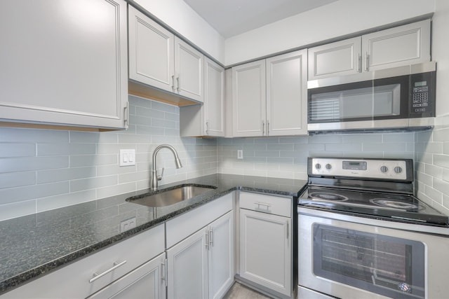 kitchen featuring dark stone counters, stainless steel appliances, tasteful backsplash, and sink